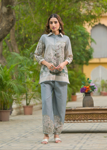 Woman in a floral blouse and pants standing in a garden setting
